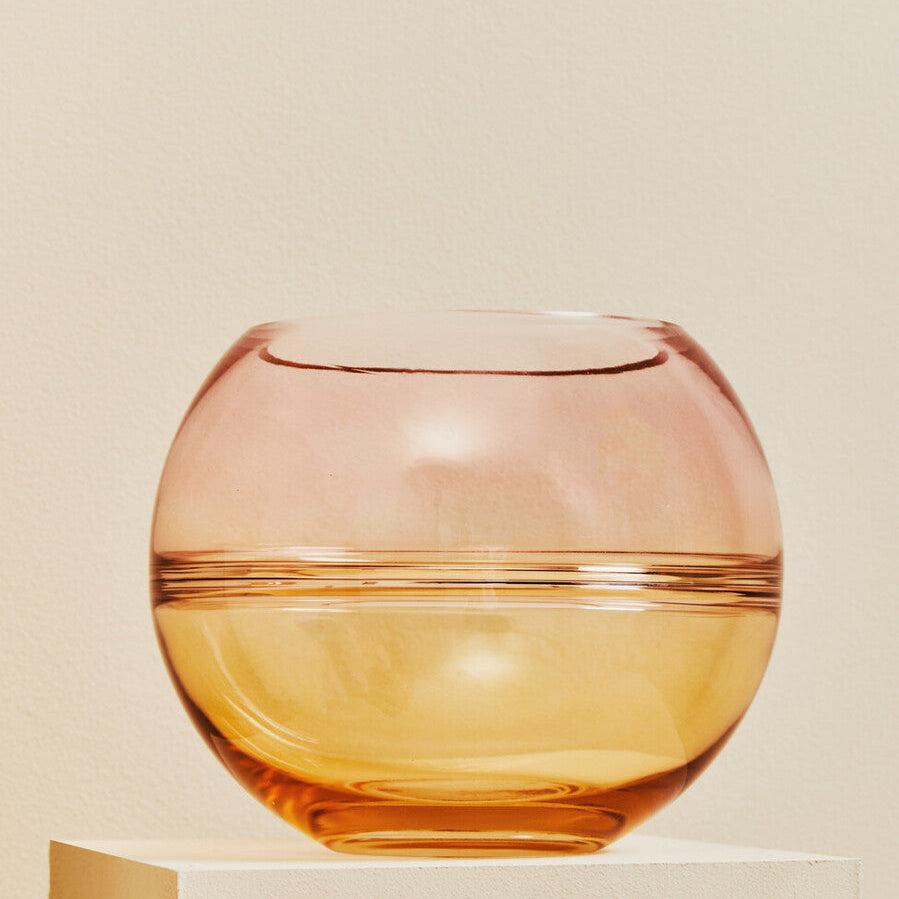 Two-toned glass bowl on a beige pedestal against a beige background