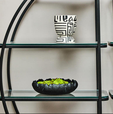 Glass shelving unit with decorative items on a plain background