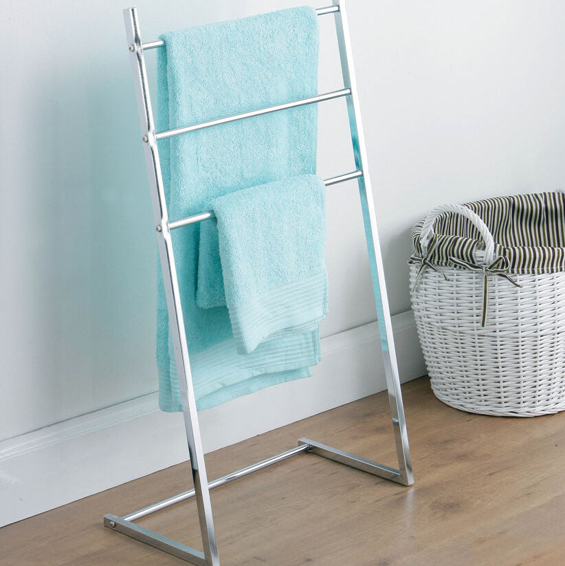Towel rack with a blue towel against a white wall with a basket on the floor.