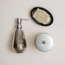 Decorative soap dispenser with a bar of soap on a small round tray against a light background