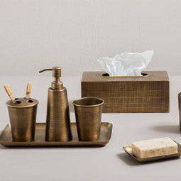 Bronze bathroom accessory set including cups, dispenser, tissue box, and soap dish on a neutral background