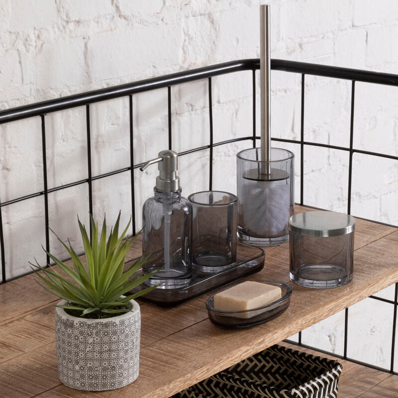 Bathroom shelf with various items including a plant, soap, and glass containers against a white brick wall.
