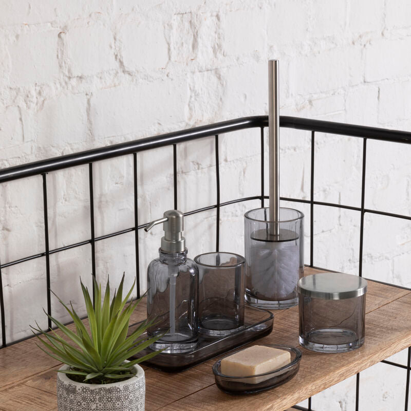 Bathroom shelf with various items including a plant, soap, and glass containers against a white brick wall.