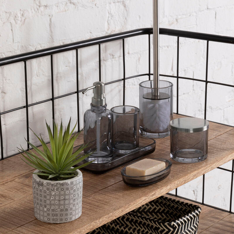 Bathroom shelf with various items including a plant, soap, and glass containers against a white brick wall.