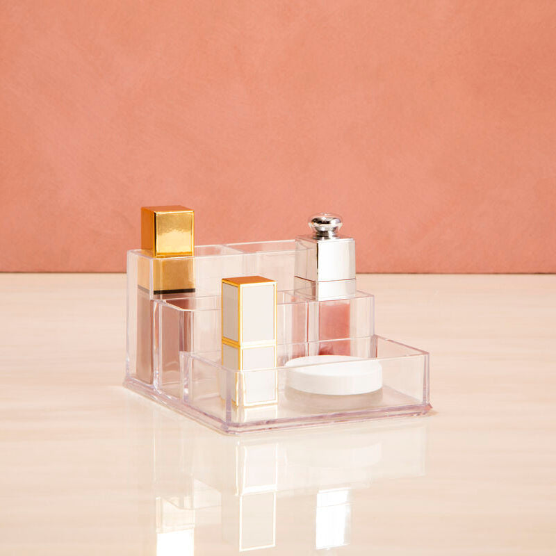 Two perfume bottles on a clear stand against a pink background