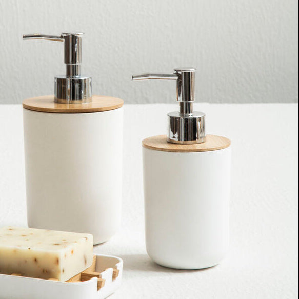 Two white soap dispensers with wooden accents on a light surface.