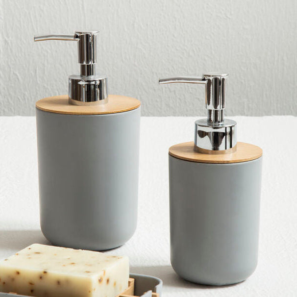 Two gray soap dispensers with wooden accents on a white surface.