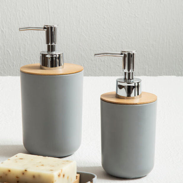 Two gray soap dispensers with wooden accents on a white surface.