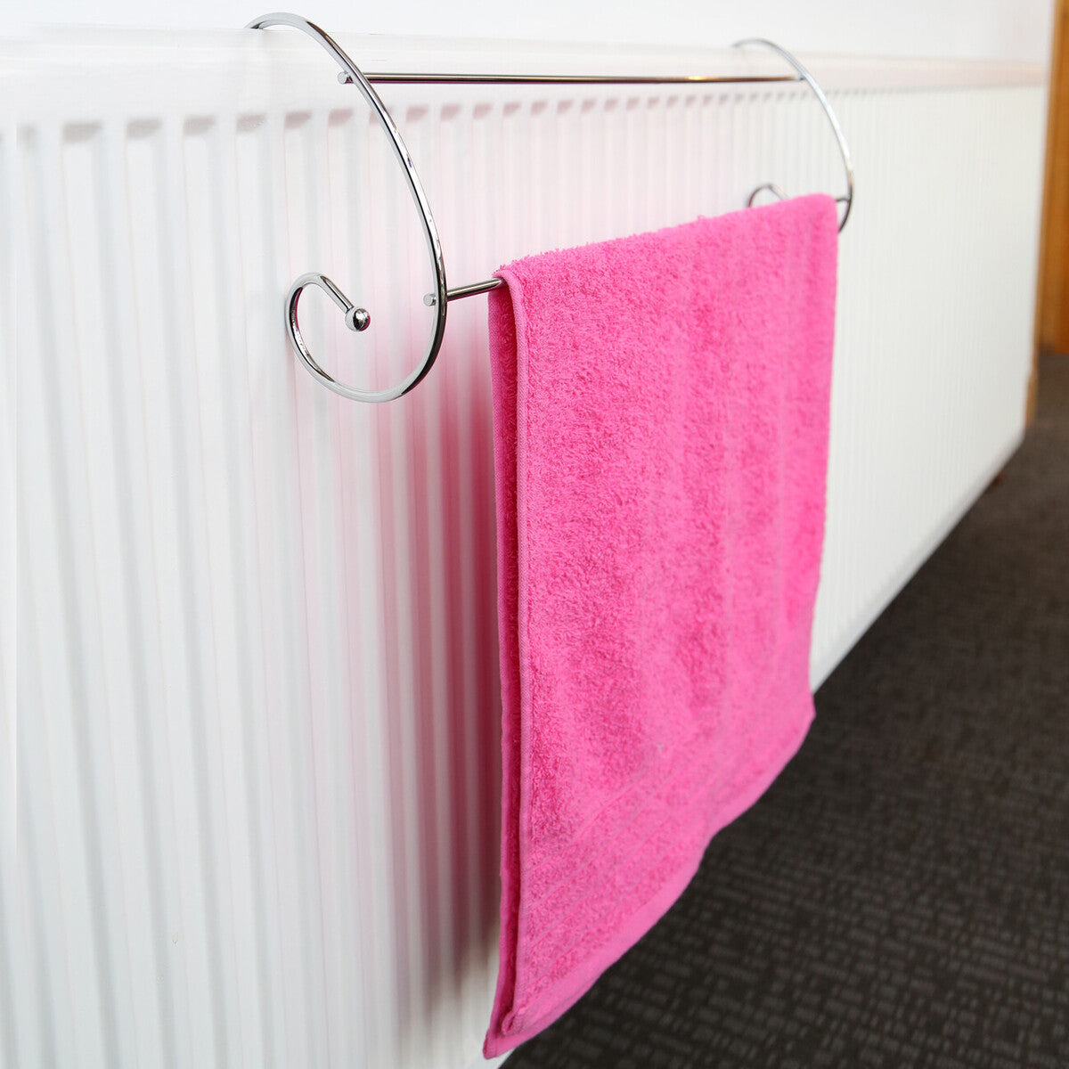 Pink towel hanging on a radiator with a decorative metal hook.