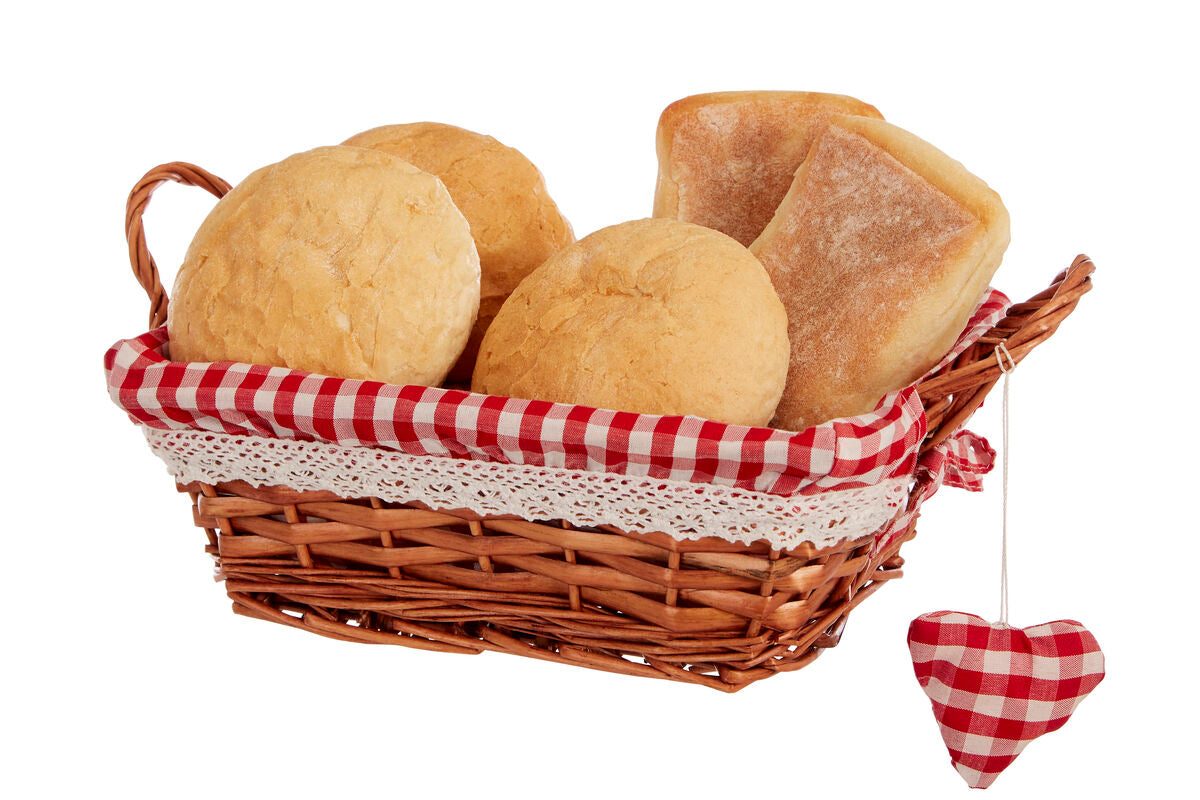 Wicker basket with bread rolls and a red and white checkered heart on a white background