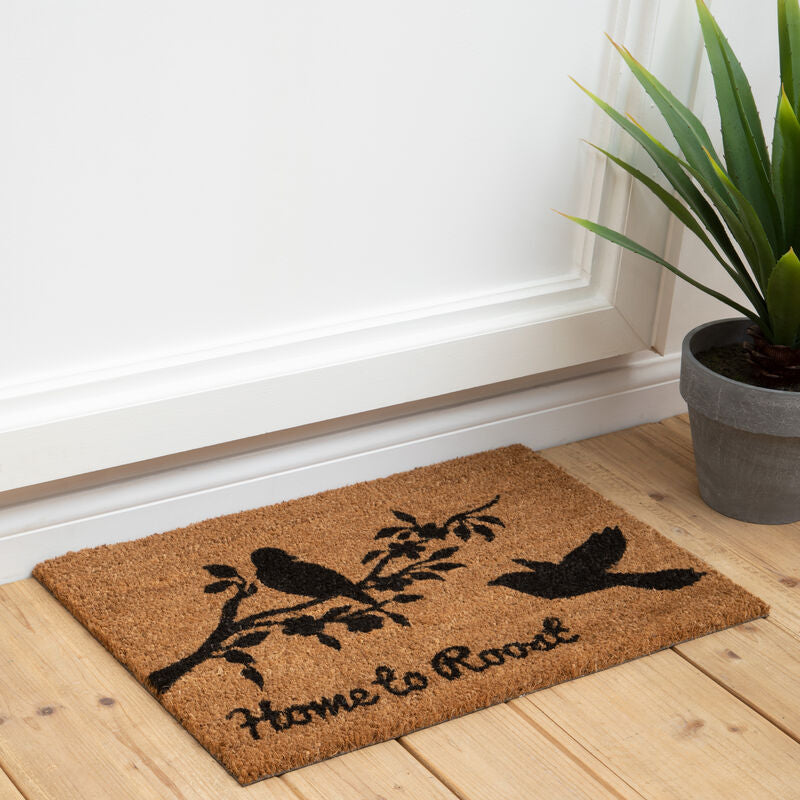 Doormat with birds design on a wooden floor next to a plant