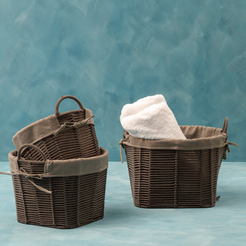 Two brown woven baskets with handles on a blue surface against a teal textured background