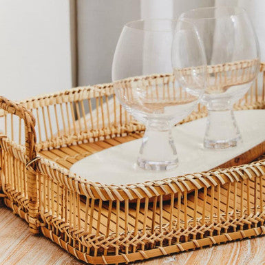 Wicker tray with glasses on a wooden surface