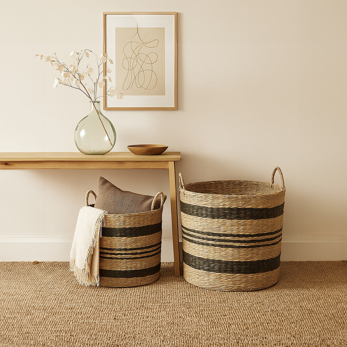 Two woven baskets on a beige rug with a wooden shelf and framed abstract art in the background.