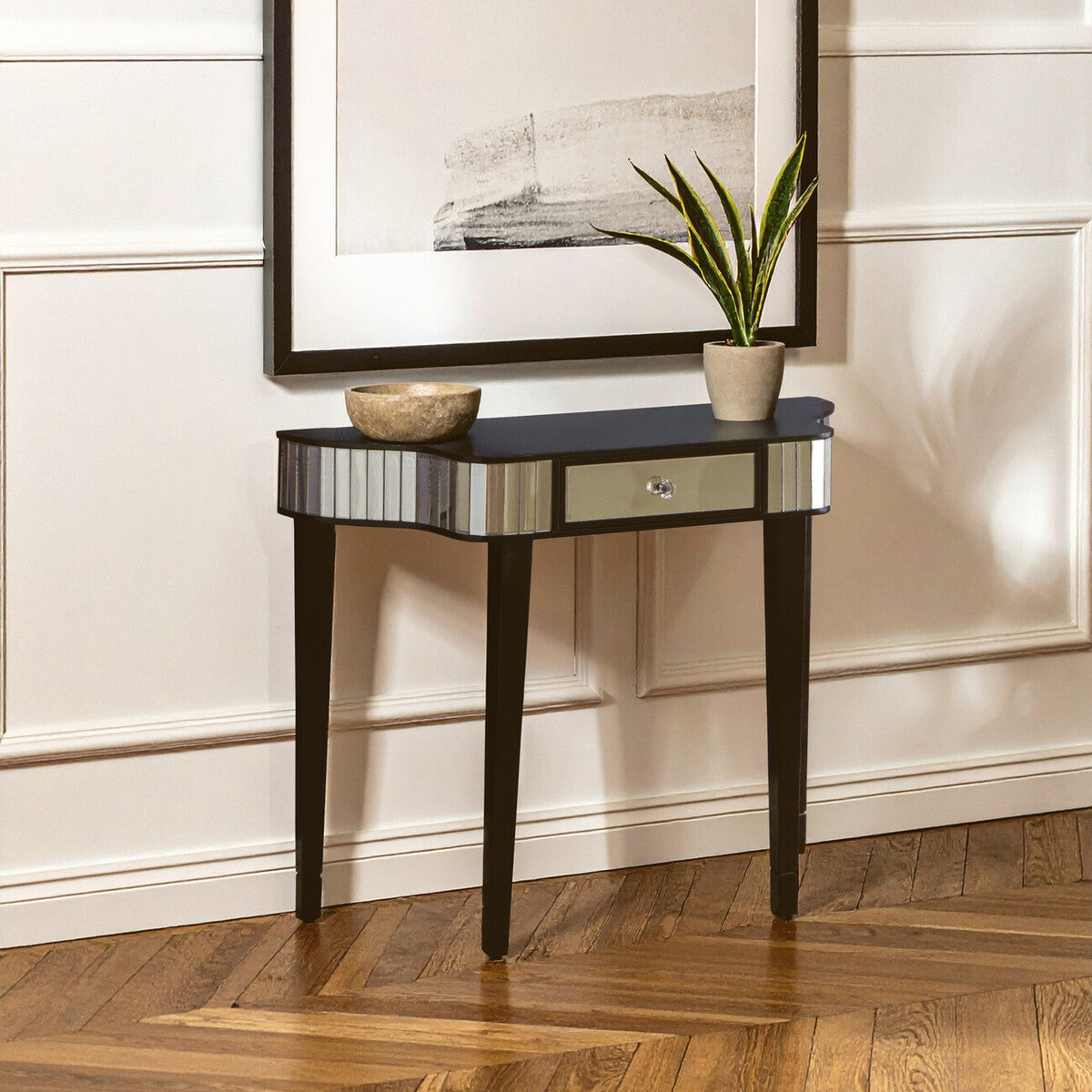 Console table with a mirror surface in a room with a framed picture and plant.
