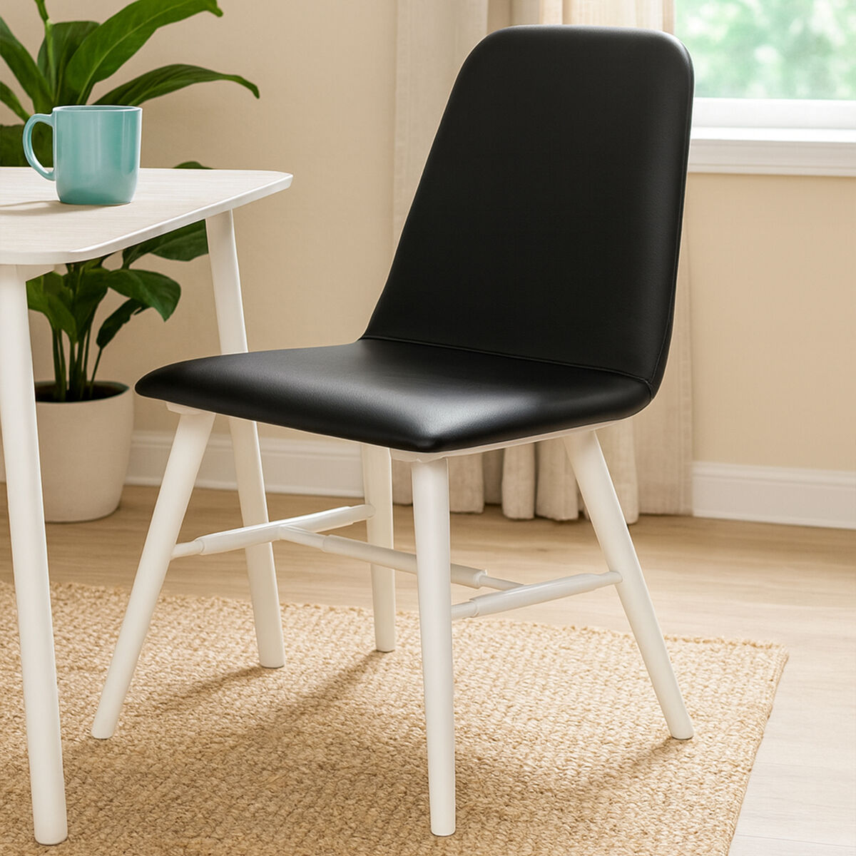 Black chair with white legs in a room with a table and plants
