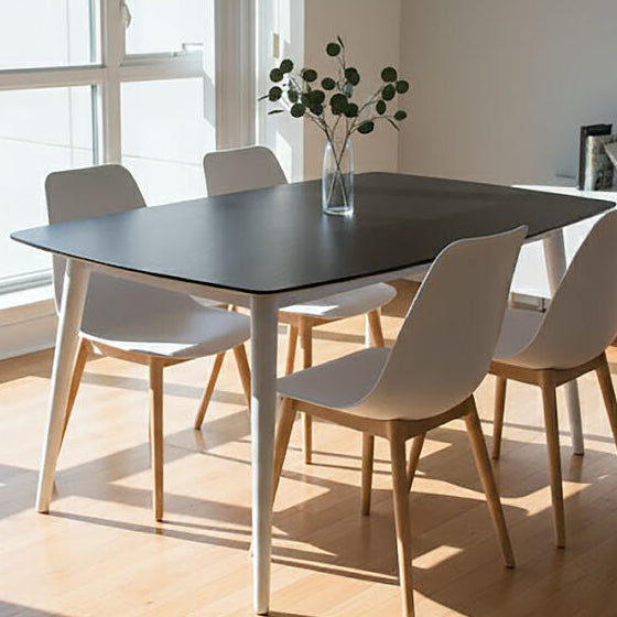 Modern dining area with a table and chairs near large windows in a well-lit room.