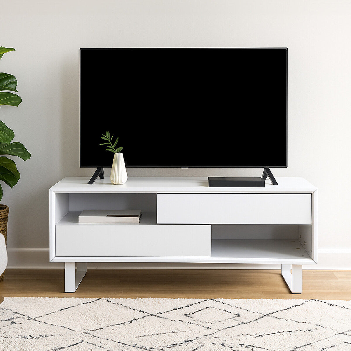 White TV stand with a black TV on a light-colored wall.