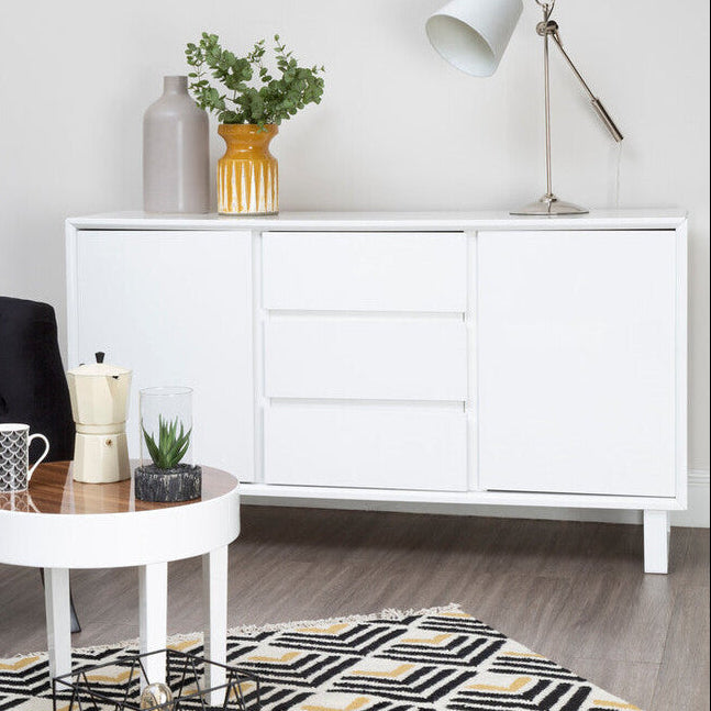 Modern living room with a white sideboard, black armchair, and decorative items.
