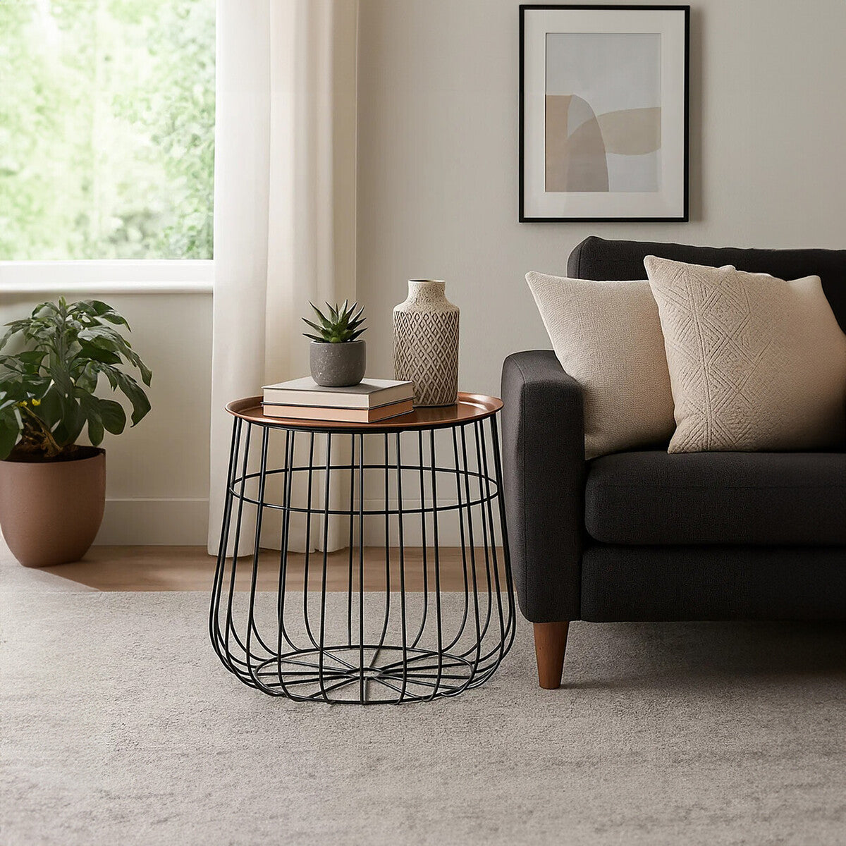 Modern living room with a black wire side table, gray sofa, and decorative items.