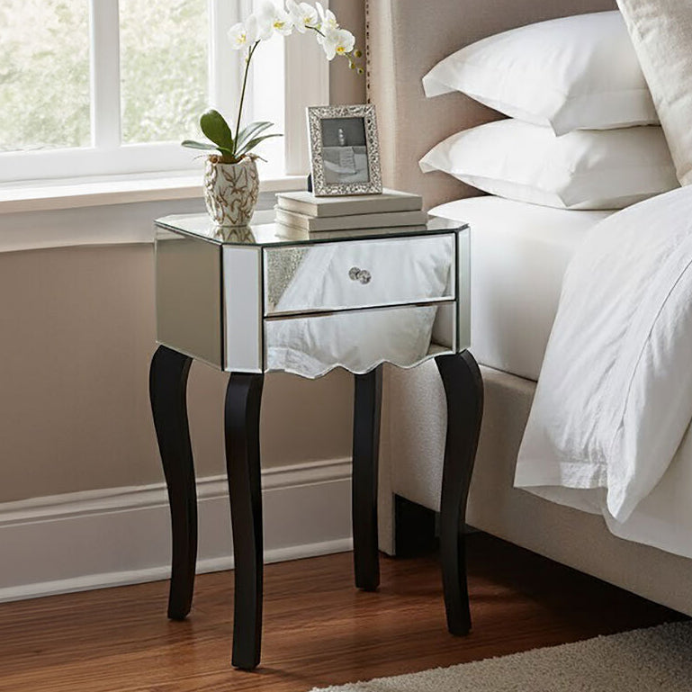 Neatly made bed with white bedding and a side table with decorative items in a bedroom.