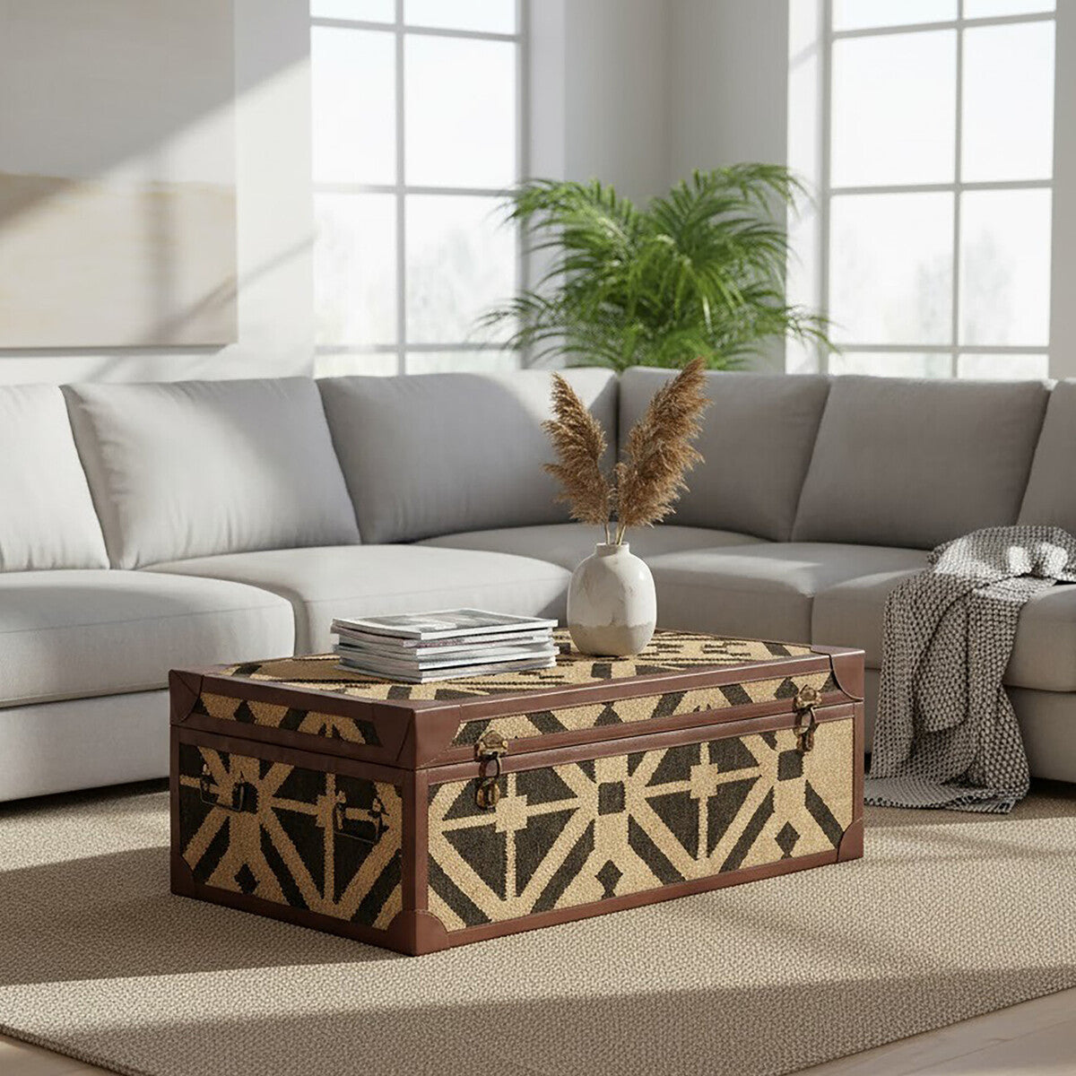 Decorative wooden chest on a coffee table in a living room with a sectional sofa and plants.