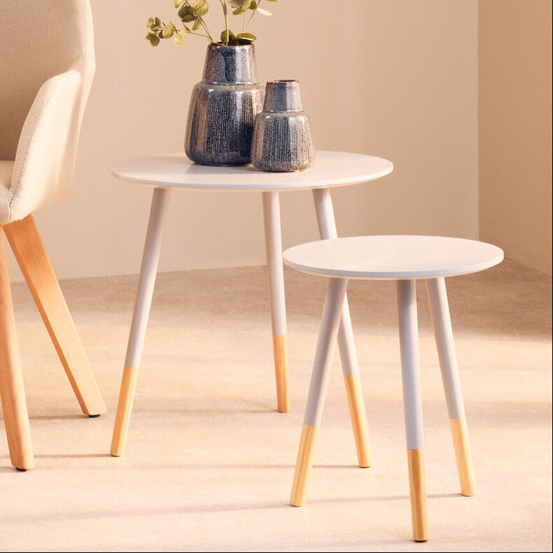 Two small round tables with white tops and gold legs, accompanied by a chair and decorative vases.