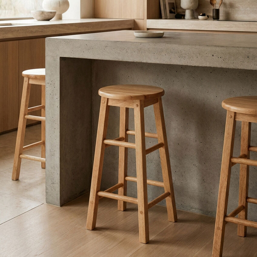 Wooden bar stools in front of a concrete countertop in a kitchen setting.