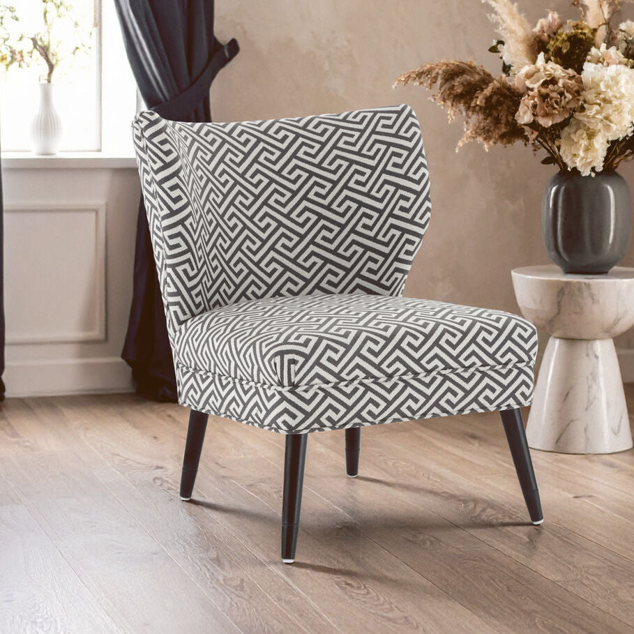 Patterned armchair in a room with a vase of flowers on a small table.