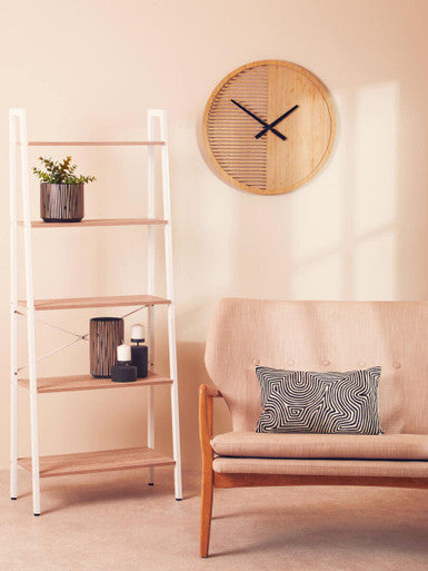 Living room with a beige sofa, decorative pillow, bookshelf, and wall clock.