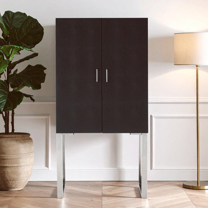 Dark wooden cabinet with silver legs in a room with a plant and lamp.