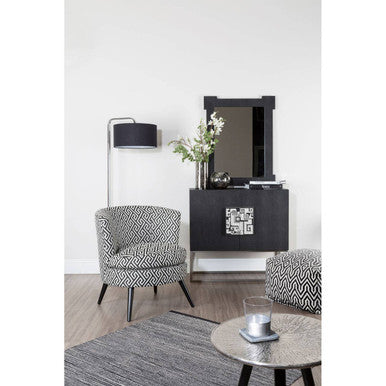 Modern living room with a black console table, patterned armchair, and round coffee table.