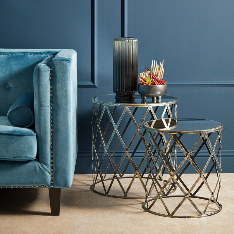 Blue sofa with decorative side tables and a vase against a blue wall.