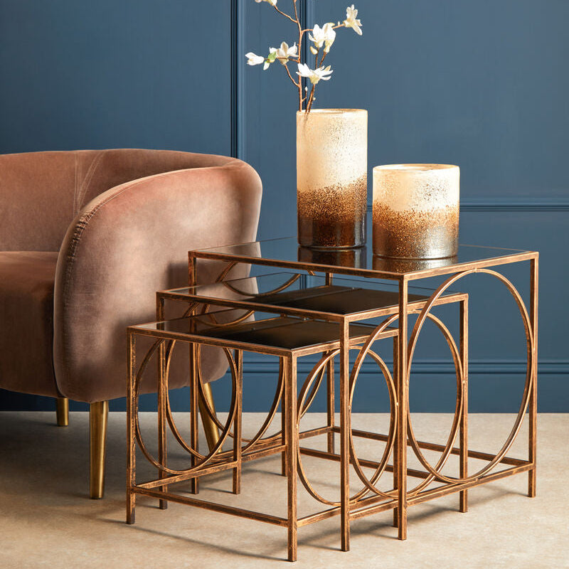 Bronze side table with a vase of flowers against a blue wall