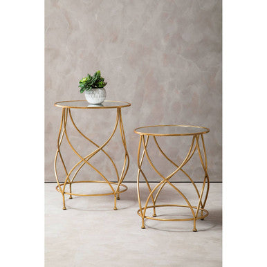 Two gold metal side tables with glass tops on a neutral background