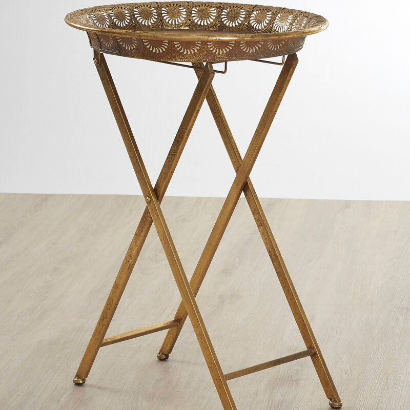 Bronze folding table with decorative top on a light wooden floor.