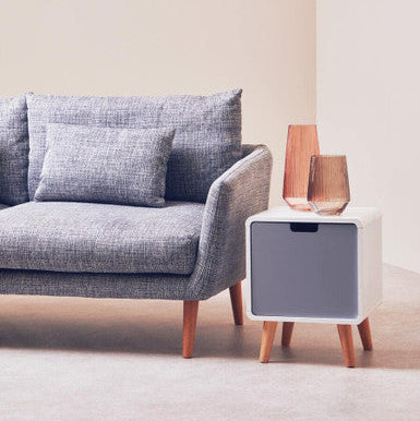 Gray sofa with a small white side table and decorative items in a minimalistic living room.