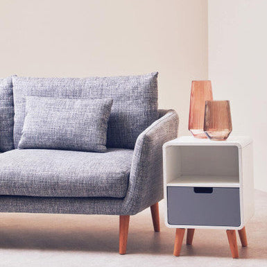 Gray sofa with a side table and decorative items in a minimalistic living room.