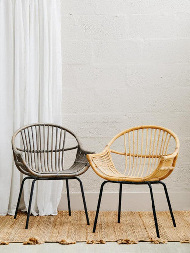 Two wicker chairs, one gray and one beige, against a white wall.