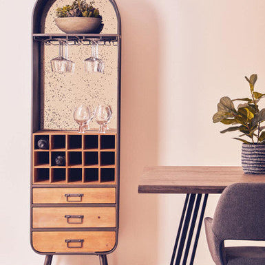 Tall wooden bar cabinet with glass holders and shelves in a room setting.