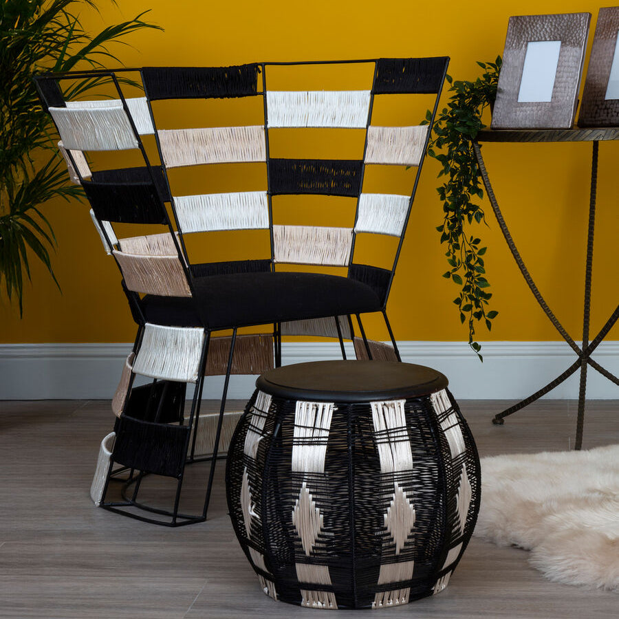 Decorative chairs and stool with geometric patterns against a yellow wall.