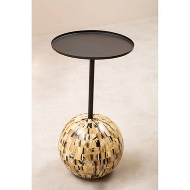 Side table with round woven base and black metal top on a beige background