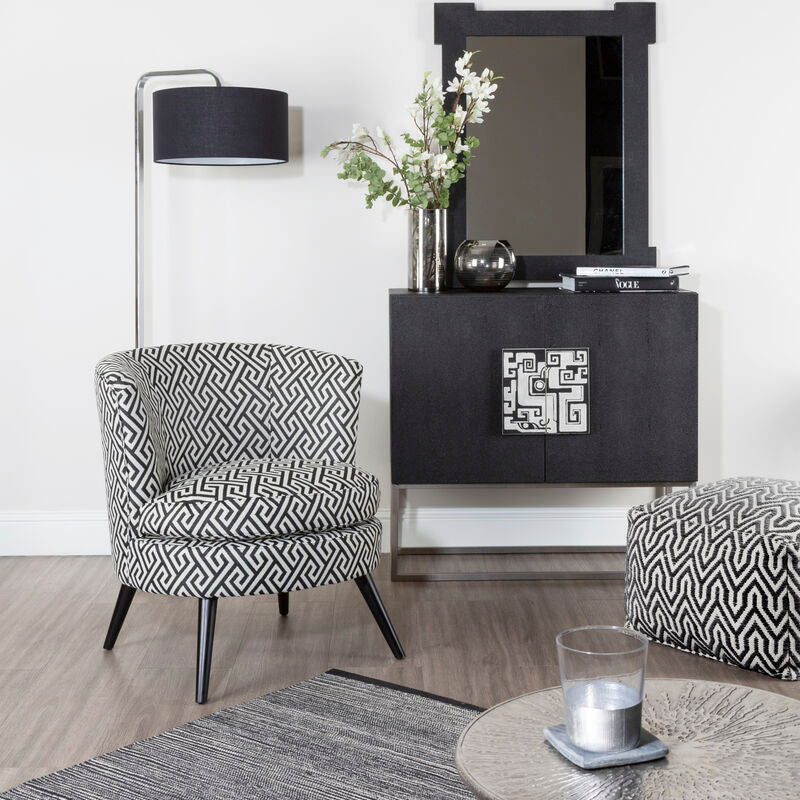 Modern living room with black and white patterned chair, side table, and lamp.