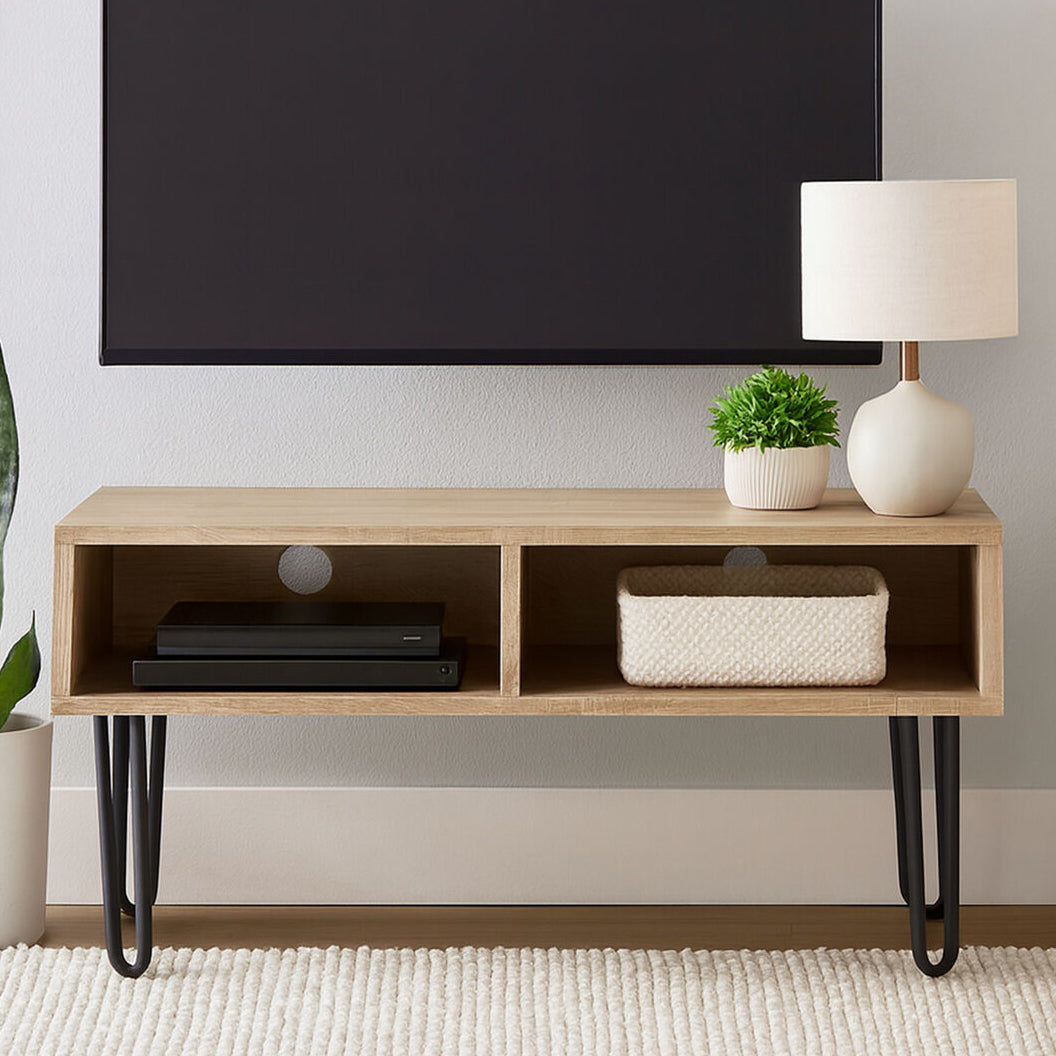 Wooden TV stand with a television mounted above it, featuring decorative items like a lamp and plants.