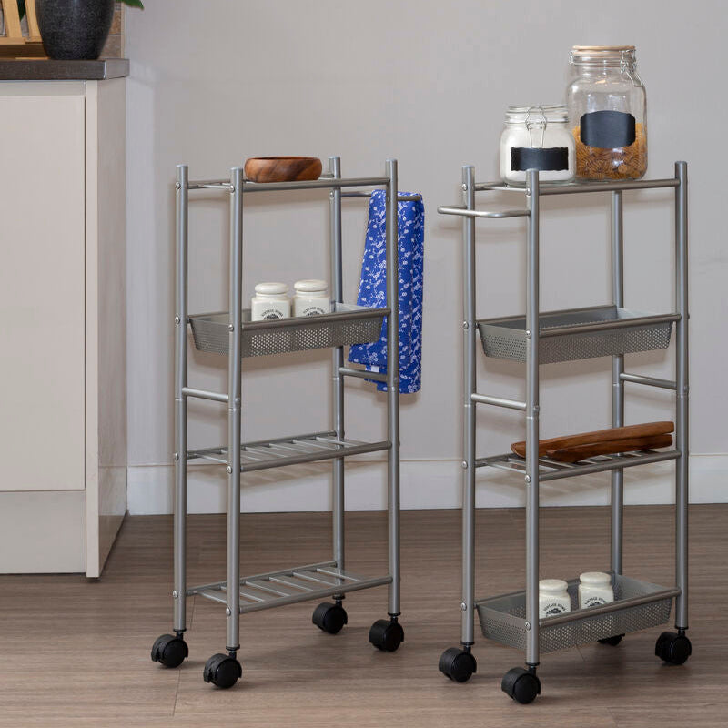 Two metal serving carts with wheels on a wooden floor against a gray wall.
