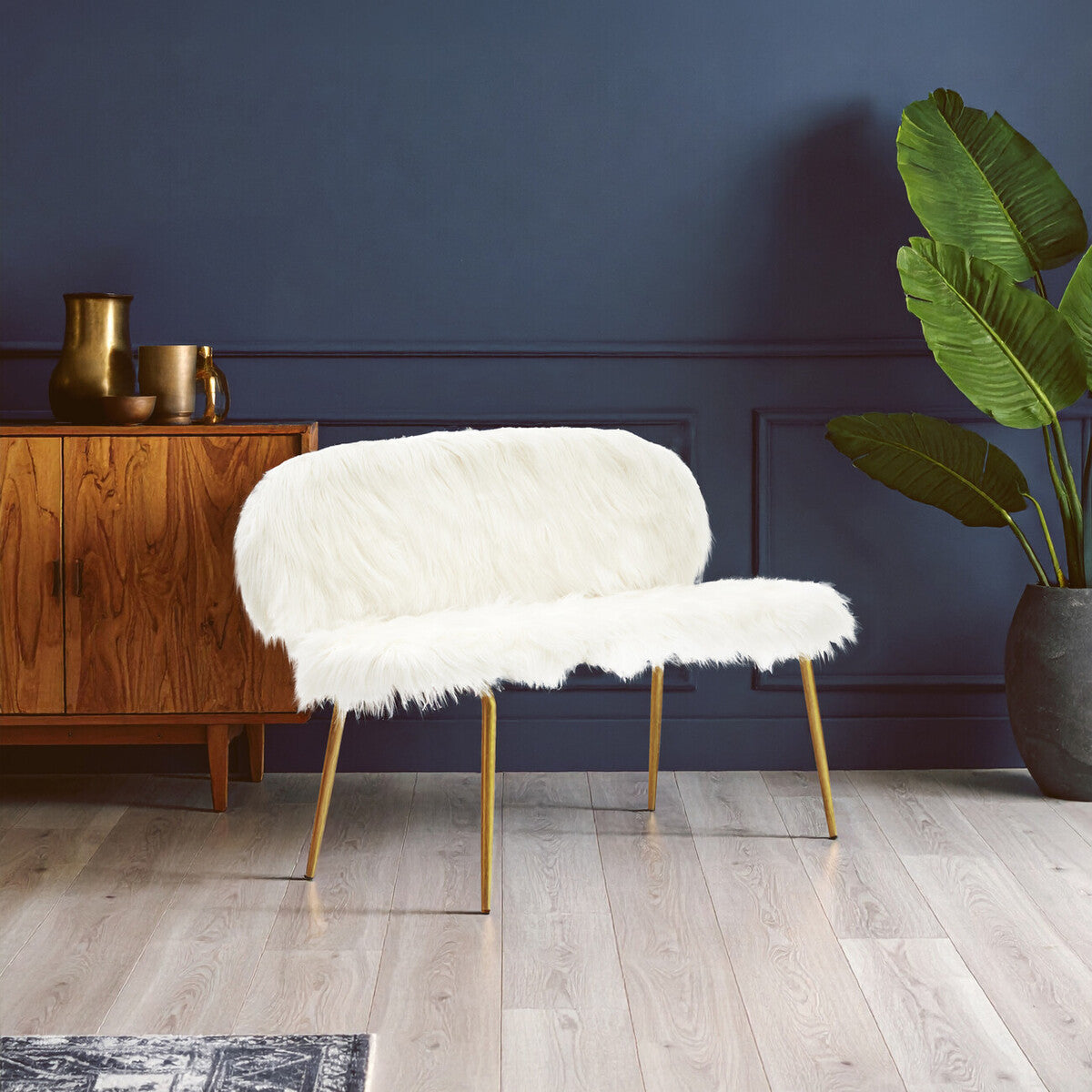 White fur chair with gold legs in a room with a wooden cabinet and plant.