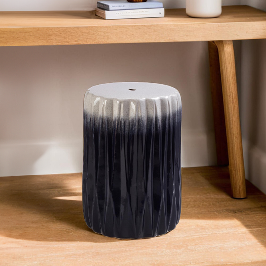 Black and white textured stool in front of a wooden table with decor items.