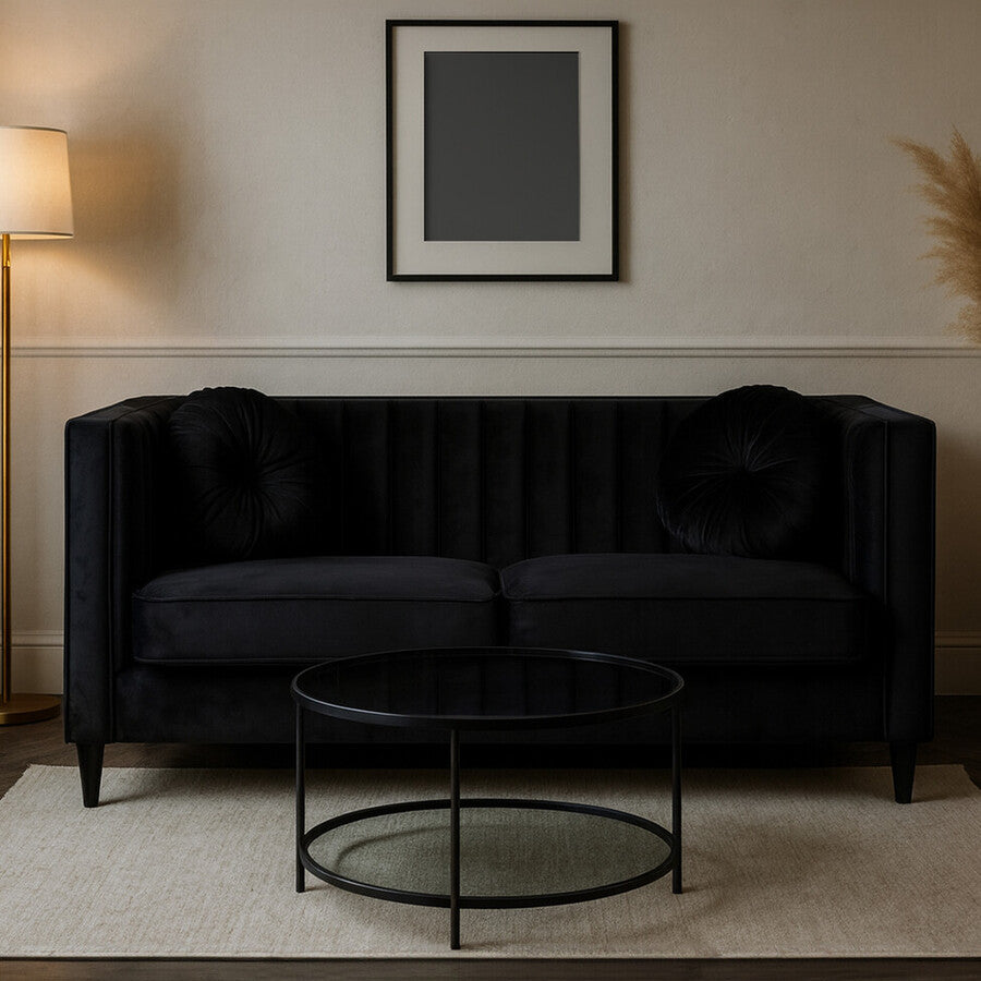 Modern living room with a black sofa, round coffee table, and framed picture on the wall.
