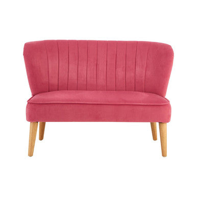 Pink velvet loveseat with wooden legs on a white background