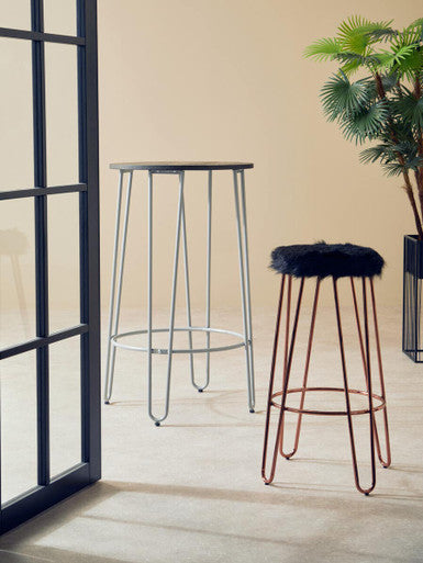 Two bar stools with metal frames and cushioned seats in a room with a plant and window.